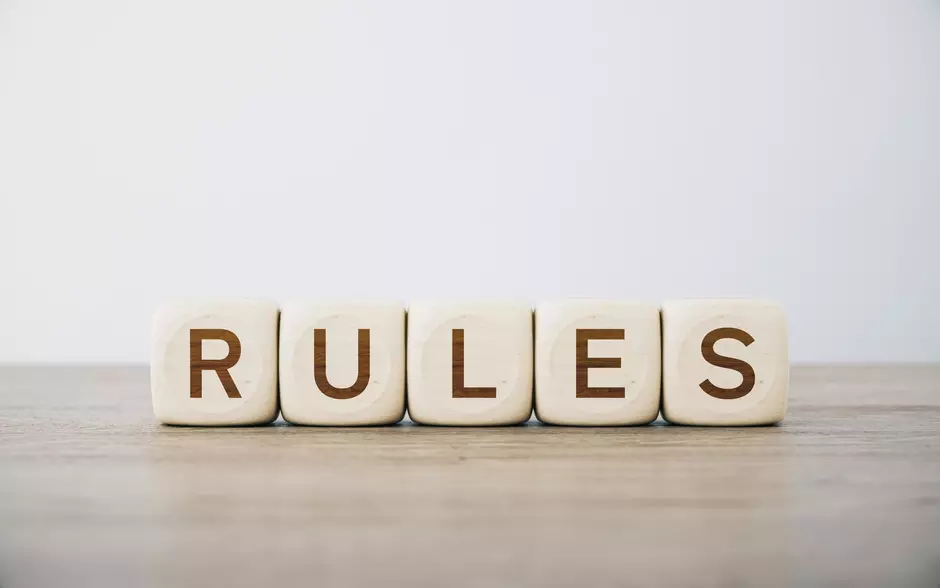 Napis "RULES" ustawiony z kostek na drewnianym blacie.
